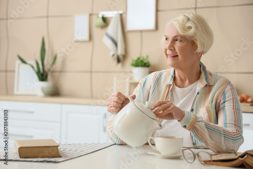 Senior woman pouring tea at...