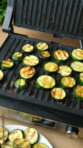 Close-up of Fresh Green Zucchini Rounds Roasting on Contact Grill.