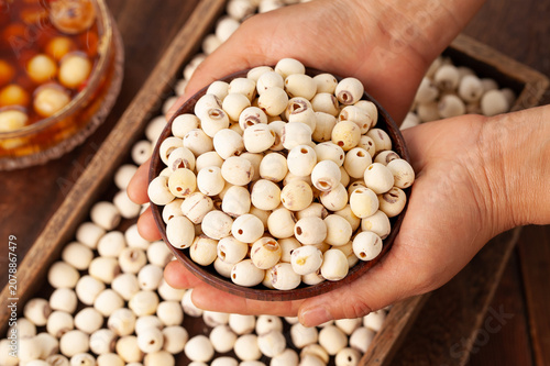 Foto White Dried Lotus Seeds in Wooden Bowl Held by Hands - Nutritional Superfood Ing