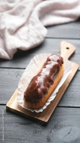 Chocolate eclair on wooden board with cloth background