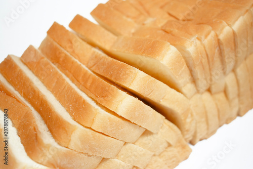 Close-up of neatly stacked sliced white bread arranged in overlapping layers, showcasing a fresh and soft texture on a clean white background.