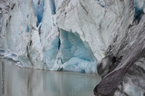 Photography close-up of a majestic glacier wall with bright blue ice and volcanic ash at a g