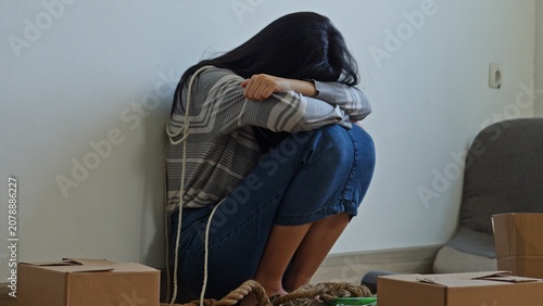 Tableau sur toile Young Female Hostage Sits Huddled On The Floor Bound By Ropes