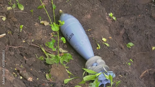 120 mm mortar round lying on the ground before deployment. Close-up of military equipment in a field setting, illustrating artillery readiness, defense operations, and battlefield logistics. Russo