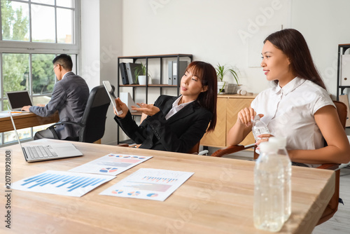 Chinese business women working with tablet computer at table in office