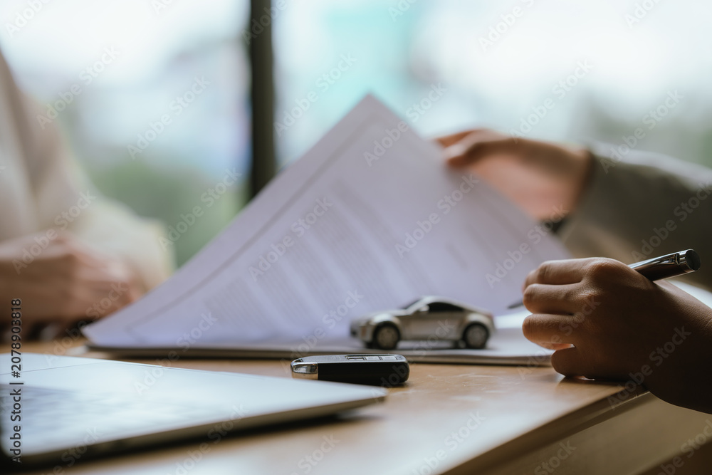 Fototapeta premium Businesswoman handing over a car key while signing a vehicle purchase or rental agreement, symbolizing automotive sales, leasing, and customer service.