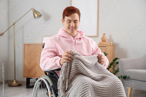 Young man in wheelchair with plaid at home