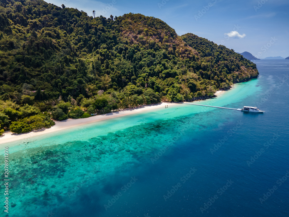 Obraz premium Aerial drone view of tropical landscape over Madam Beach of Nyaung Oo Phee Island with tour boat anchoring on the floating dock in the Mergui Archipelago, Myanmar. Beautiful Andaman sea in Burma