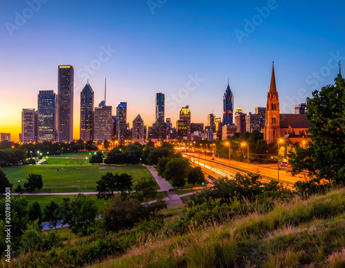 Vibrant Cityscape at Dusk with Illuminated Skyline and Lush Green Park.