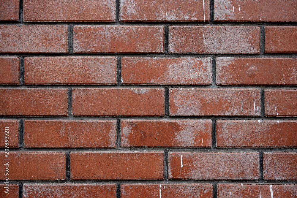 Obraz premium Texture of a weathered red brick wall with white paint stains and splatters forming a grunge architectural background