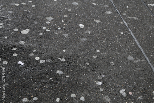 Old bubblegum stains on a black concrete street surface. Dirty asphalt with white marks. Outdoor closeup photo.