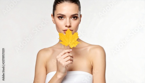 A woman holds a vibrant yellow leaf in front of her face