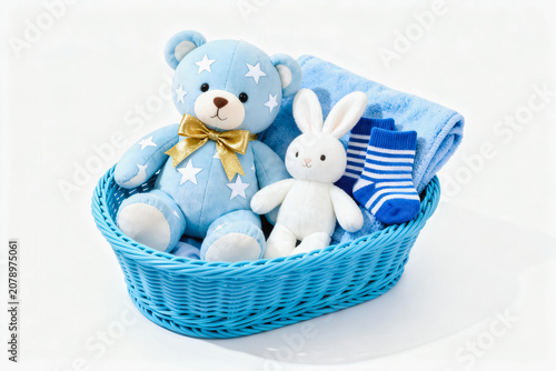 A blue woven basket holds baby items including a star-patterned teddy bear, plush rabbit, striped socks, and blanket.