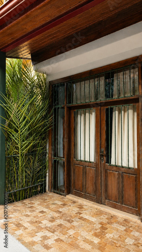 serene wooden door with glass panels and metal bars on outdoor porch area, traditional home decor setting, clean and bright interior design, brown and green natural materials.