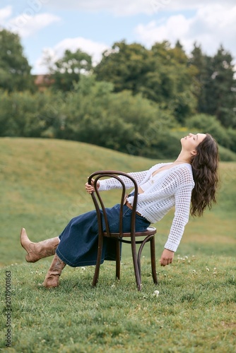 Young woman enjoys a serene afternoon in the park while embracing fashion and nature