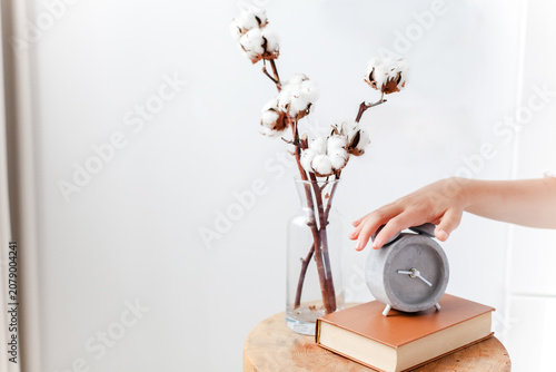 Hand turning off an alarm clock in cozy bedroom interior. Awakening, sleep quality and woman morning routine. Concept of biological clock, circadian rhythm