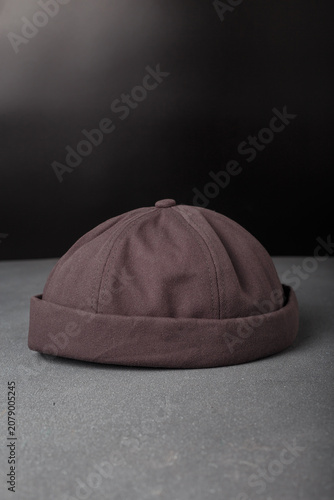Grey cotton beanie cap or docker hat on black backdrop. Closeup shot, copy space