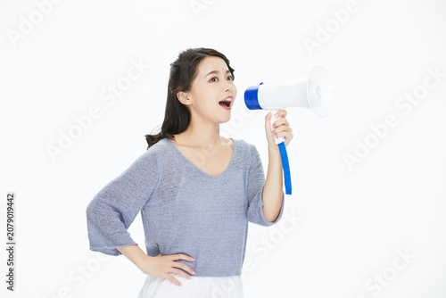 Photography Young woman shouting through megaphone on white background