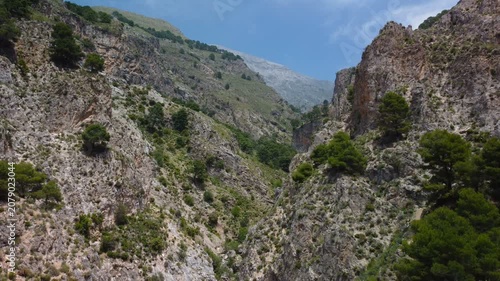 Aerial view of suspension bridge of 'El Saltillo Canillas de Aceituno' in the beautiful mountain landscape of Canillas de Aceituno on a sunny day, Malaga, Spain
