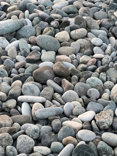 Photography Smooth gray pebbles covering rocky beach surface with natural stone texture and