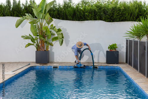 Pool worker deploying robotic pool cleaner into swimming pool