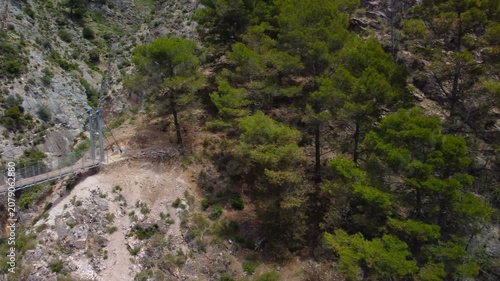 Aerial view of suspension bridge of 'El Saltillo Canillas de Aceituno' in the beautiful mountain landscape of Canillas de Aceituno on a sunny day, Malaga, Spain