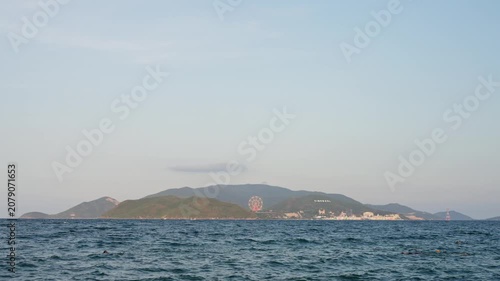 Nha Trang Vietnam. 01 06 2026 Distant island observed from calm sea at midclip with swimmers in foreground
