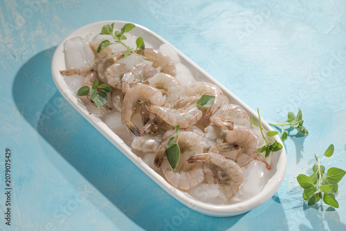 Raw pacific white shrimp prawn peeled with tail on ice.Top view. Copy space.