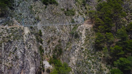 Aerial view of suspension bridge of 'El Saltillo Canillas de Aceituno' in the beautiful mountain landscape of Canillas de Aceituno on a sunny day, Malaga, Spain