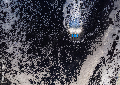 Aerial view of a water aerator creating white foam in a dark pond, used for aquaculture in Kecamatan Ayah, Jawa Tengah, Indonesia.