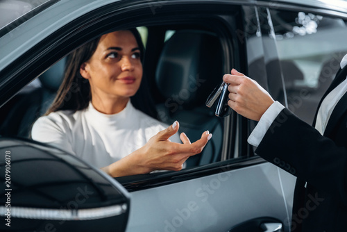 Fotografie Woman receiving car keys from a salesperson while sitting in a vehicle, showcasi