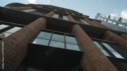 Bottom view of a modern brick building with mirrored windows