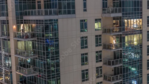 Residential building exterior aerial timelapse showcasing the environment in Dubai. Countless residential balconies and illuminated rooms fill the immense concrete structure.