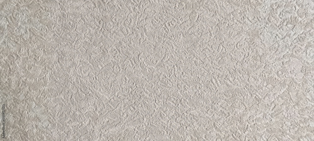 Fototapeta premium Close up of beige textured wallpaper with an intricate swirling relief pattern resembling abstract organic foliage. Background or interior design concept.