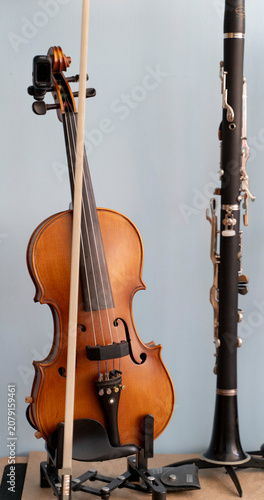 Vertical portrait of a classical wooden violin and a black clarinet on stands side by side