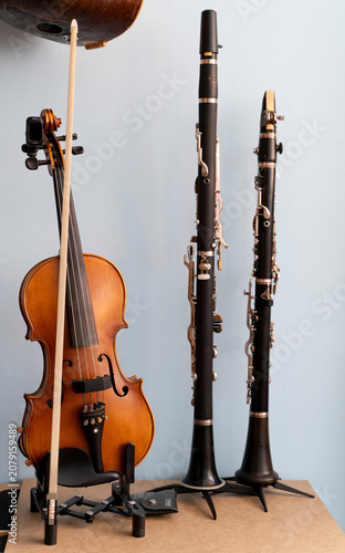 Vertical portrait of a classical wooden violin and a black clarinet on stands side by side