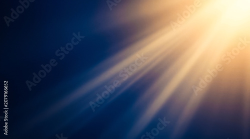 Golden sunlight rays shining through dark blue sky, abstract nature background for inspirational design