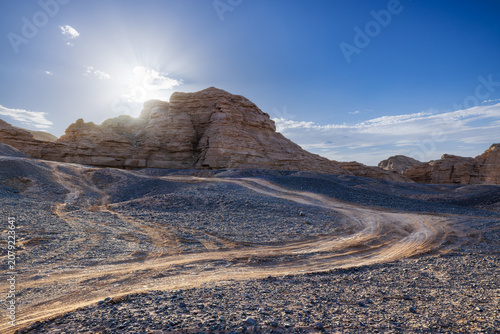 Bright sunlight over the arid Gobi desert landscape with yardang landforms and stony ground in Xinjiang, China