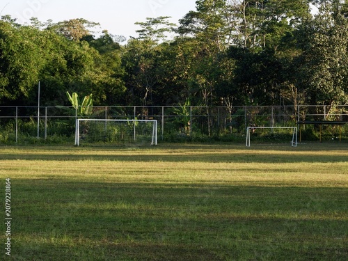 A scenic outdoor sports ground showcasing vibrant green lawns and vacant soccer nets in a quiet countryside park.