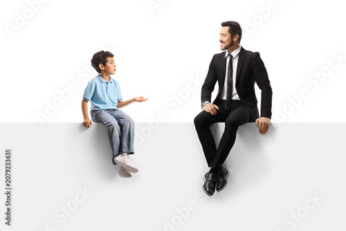 Businessman and a boy sitting on a white panel