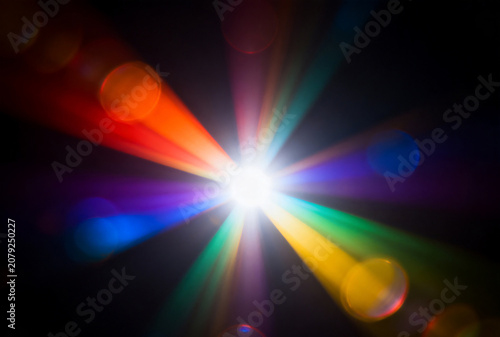 Bright multicolored starburst with lens flare on black background