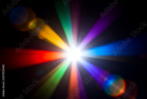 Bright multicolored starburst with lens flare on black background