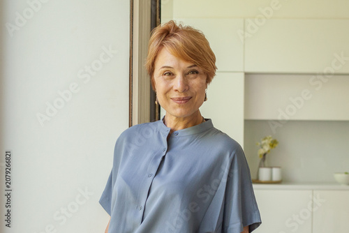 Attractive smiling 55 years old woman at home portrait
