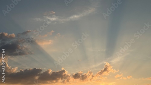 Obraz na plátně Crepuscular rays breaking through dark clouds in evening sky