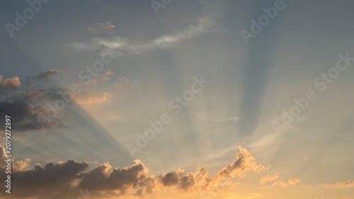 Fotografie Dramatic sun rays breaking through clouds in evening sky