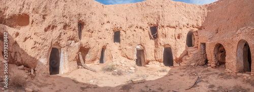 Wide view of traditional troglodyte houses carved into rock in Matmata, Tunisia. Ancient underground dwellings in arid desert landscape, historic Berber architecture and cultural heritage site