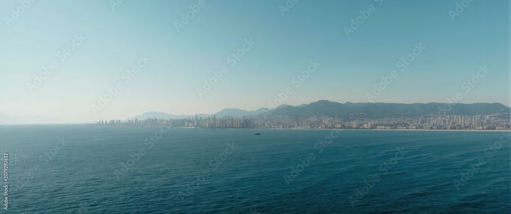 Fototapeta premium Coastal city skyline viewed from the ocean under clear sky