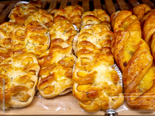 Obraz na plátně Freshly baked golden pastries and savory breads displayed on a wooden bakery shelf
