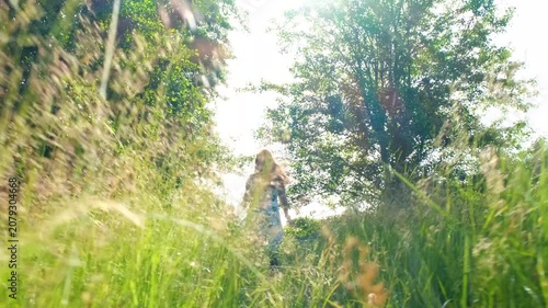 Young woman running through green grass in sunny summer meadow