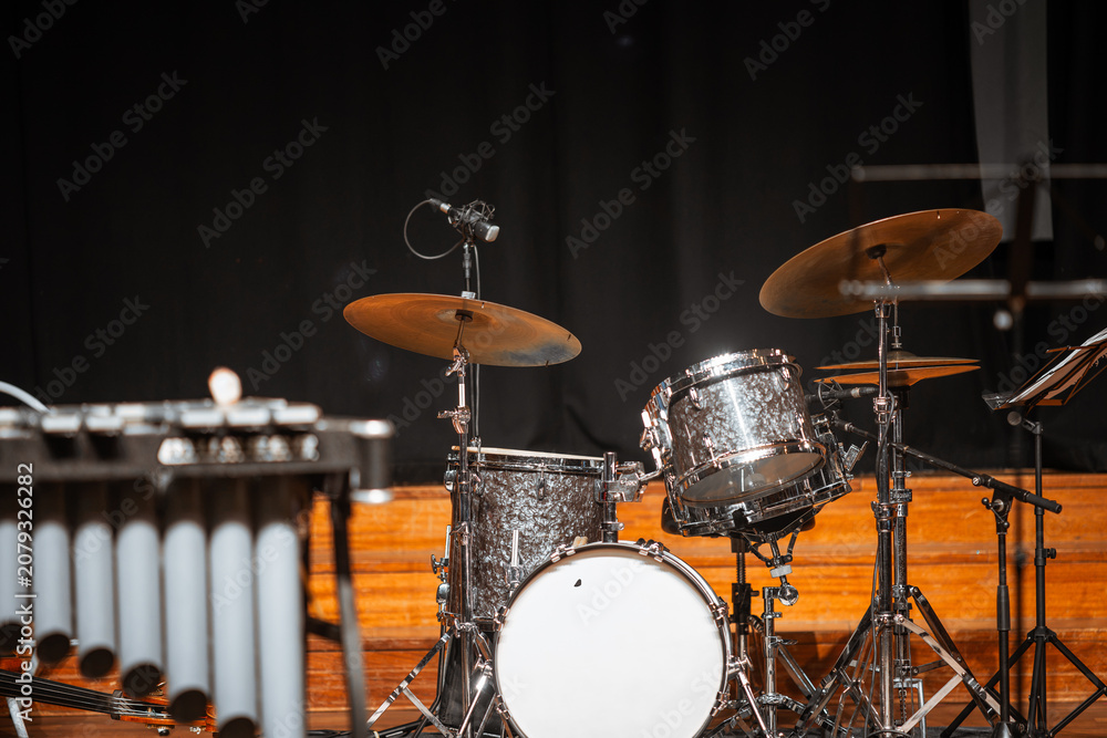 Fototapeta premium Selective focus on a polished drum set with cymbals and microphones on a wooden concert stage, ready for musicians before a live performance